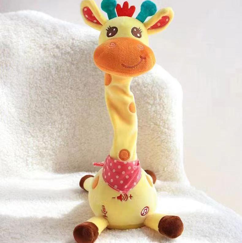 A yellow giraffe plush toy with a long neck, brown spots, a pink polka-dot bandana, and colorful ears, sitting on a white textured blanket.
