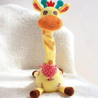 A yellow giraffe plush toy with a long neck, brown spots, a pink polka-dot bandana, and colorful ears, sitting on a white textured blanket.